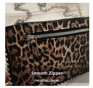 Detail of premium leopard print handbag with smooth metal zipper and silver chain straps