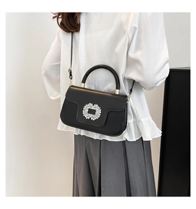 Détail du sac à main plissé noir avec une boucle rectangulaire ornée de cristaux brillants