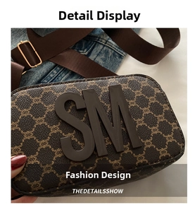 Detail view of a vintage brown square crossbody bag with SM logo and wide nylon strap