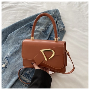 Detail of a brown leather shoulder bag with a gold D-shaped buckle and crossbody strap