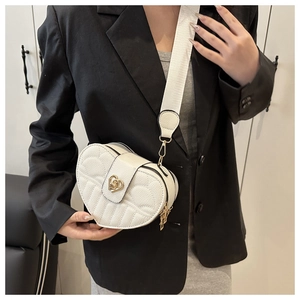 Detail of white heart-shaped crossbody bag with gold buckle and wide shoulder strap