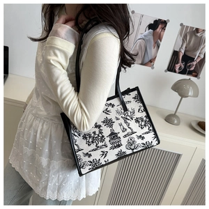 Foto lifestyle di una borsa tote in tela con motivo toile francese e manici in pelle