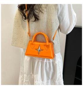 Elegante borsa a tracolla arancione con stella d'argento indossata da modella in set minimal