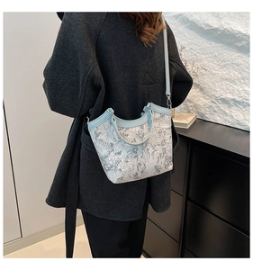 Detailed embroidery on light blue lace crossbody bucket bag with leather handles