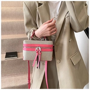 Detail of box-shaped canvas crossbody bag with pink leather trim and dual zip tassels