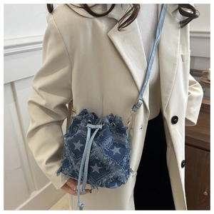 Close-up of denim bucket bag featuring white star patterns and vintage frayed edge details