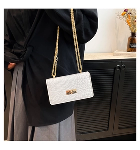 Gros plan du sac bandoulière blanc à motif croco avec chaîne dorée et fermoir métal