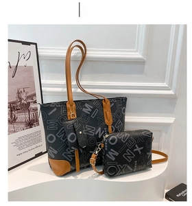 Detailed view of the black letter-print tote bag with brown leather handles and small pouches