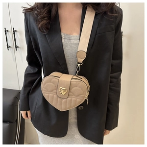Detailed view of beige heart-shaped bag with litchi texture and gold twist lock clasp