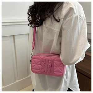 Detailed close-up of quilted pink leather crossbody bag with broad shoulder strap