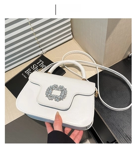 Détail d'un sac à main blanc avec boucle en cristal brillant et poignée raffinée