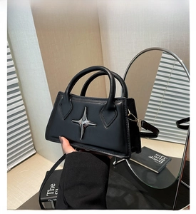 Dettaglio mini borsa a tracolla nera con decorazione a stella in metallo argento e manico