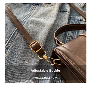 Detail of adjustable shoulder strap with gold-tone metal buckle on brown leather bag