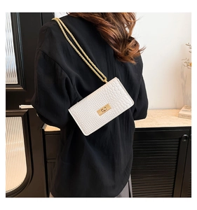 Vue détaillée du sac bandoulière blanc à motif crocodile avec boucle dorée et chaîne
