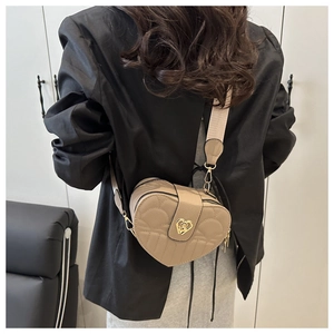 Detail of beige quilted heart crossbody bag with gold heart-shaped metal lock and wide strap