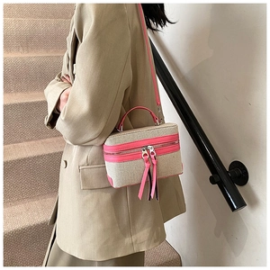 Detail of canvas box bag featuring pink leather trim and stylish long tassel zippers