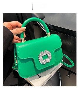 Détail du sac à main vert avec boucle en strass sur des livres blancs, style élégant