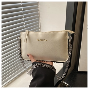Detail of beige lychee textured leather crossbody bag with gold FASHION text and studs