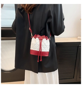 Detail of red and white quilted bucket bag showing chain strap and drawstring closure