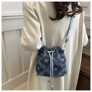 Detail of star pattern tie-dye denim bucket bag with frayed edges and drawstring closure