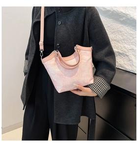 Close-up of pink jacquard bucket bag with floral texture and crossbody strap details