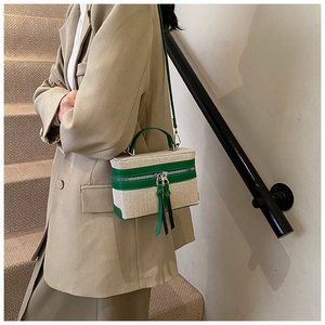 Detail of elegant small box handbag with green leather trim and tassel zippers