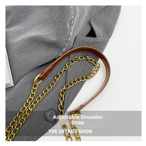 Detail of adjustable shoulder strap with gold chain and brown leather on gray blazer