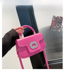 Détail du sac bandoulière rose fuchsia avec boucle ronde en strass et poignée haute