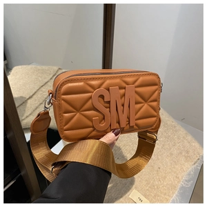 Close-up of brown quilted crossbody bag featuring SM logo and wide fabric shoulder strap