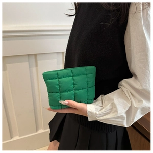 Detalle de neceser verde acolchado con textura suave y costuras de diseño cuadrado