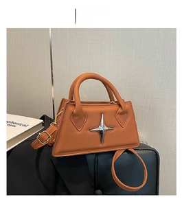 Dettaglio borsa a mano in pelle marrone con ornamento a stella d'argento e doppi manici
