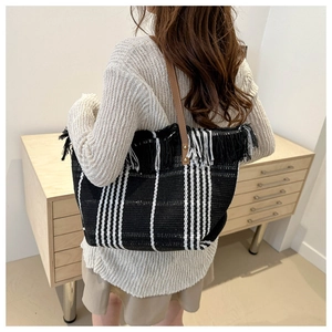 Close-up of black and white striped canvas tote with fringe trim and leather straps