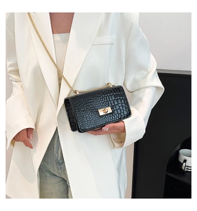 Détail du sac bandoulière noir motif crocodile avec chaîne dorée et fermoir métallique