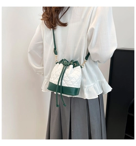 Detail of color-block quilted bucket bag with drawstring closure and golden chain