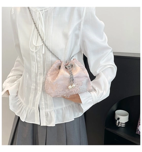 Détail du sac seau en soie rose avec chaîne argentée et perles porté par le mannequin