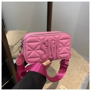 Detailed close-up of pink camera bag with wide strap, SM logo, and quilted stitching