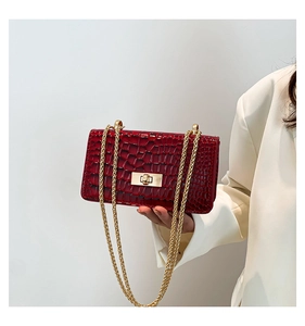 Détail du sac en cuir verni croco rouge foncé avec chaîne dorée et fermoir rotatif
