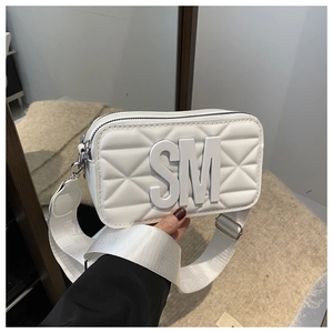 Close-up of white crossbody bag with quilted texture and silver metallic hardware