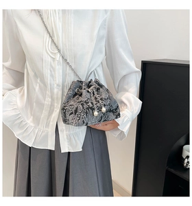 Détails d'un sac seau noir avec texture jacquard et pendentifs en perles blanches