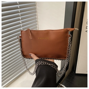 Macro detail of brown PU leather crossbody bag featuring silver rivets and metal chain strap