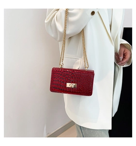 Détail du sac en cuir bordeaux à motif crocodile avec chaîne dorée et fermoir métal