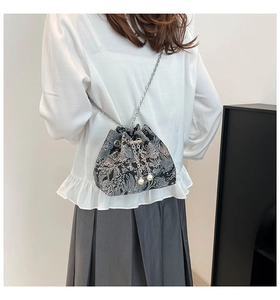 Détail d'une broderie florale sur un sac seau noir avec chaîne argentée et perles