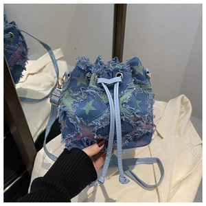 Detail of light blue denim bucket bag with star prints and frayed edges design