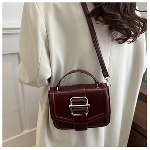 Detail of burgundy vintage square bag with gold metallic buckle on a white blazer