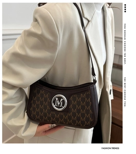 Detail of vintage monogram shoulder bag with metal M logo shown on a white blazer