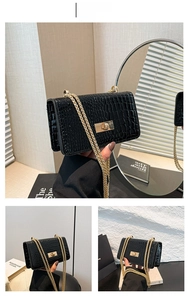 Détail du sac en cuir verni gaufré crocodile noir avec fermoir doré et bandoulière chaîne