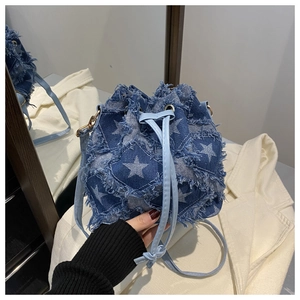 Detail of blue denim bucket bag with white stars and frayed edges in a lifestyle view