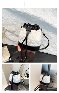 Detail of quilted drawstring bucket bag with black and white contrast and gold chain