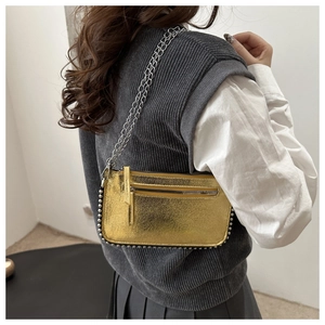 Detail of metallic gold shoulder bag featuring silver bead trim and dual chain straps
