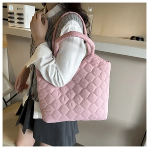 Close-up of pink quilted puffer bucket bag featuring soft embroidery and tote handles